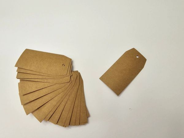 A set of brown paper tags with holes, arranged on a white surface.