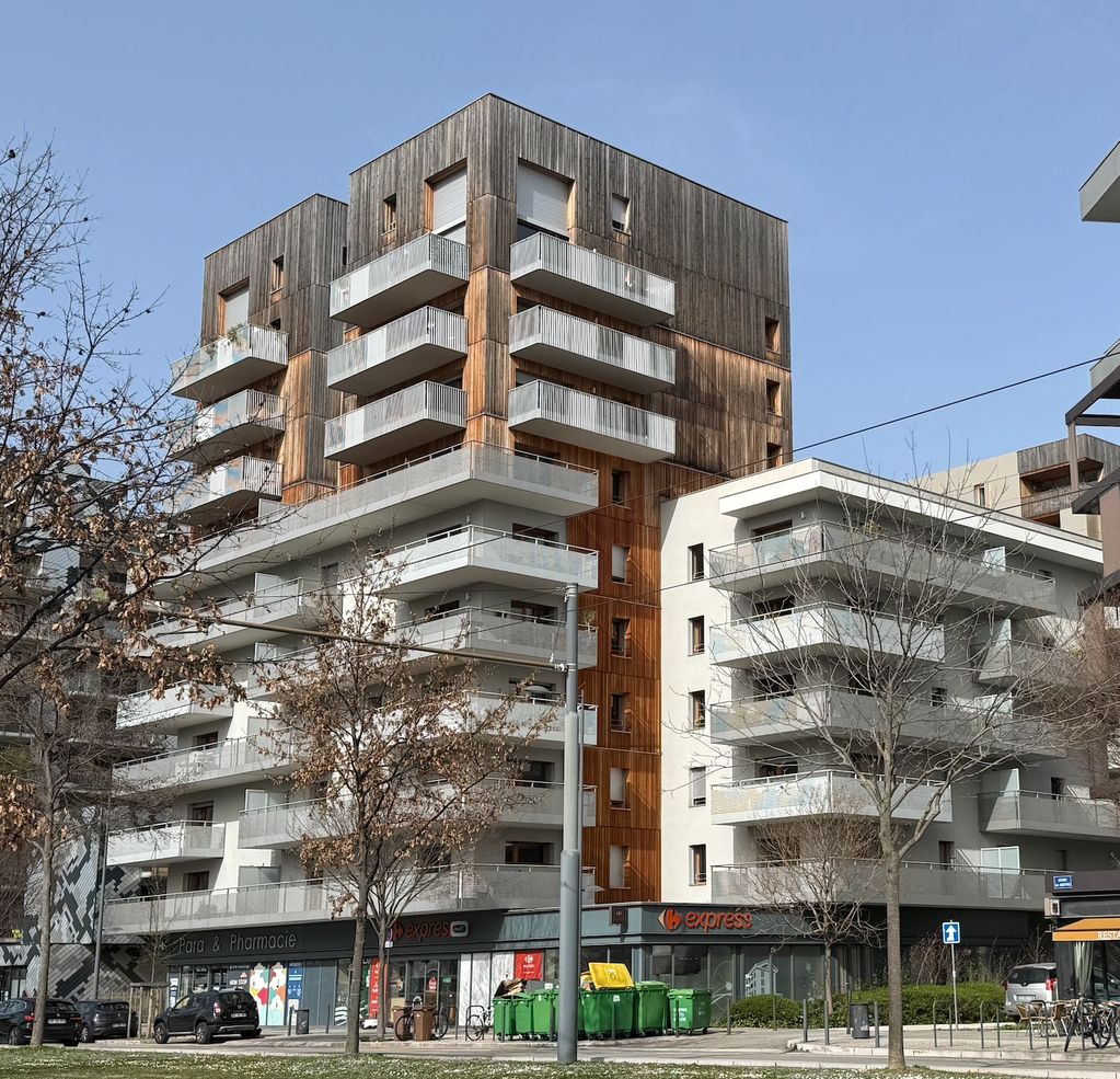 Immeuble moderne avec balcons en bois et béton sous un ciel bleu.