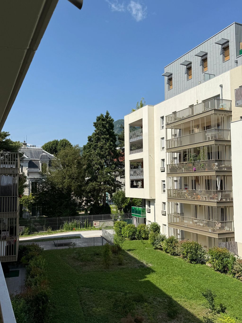 Immeuble moderne avec balcons et jardin vert.