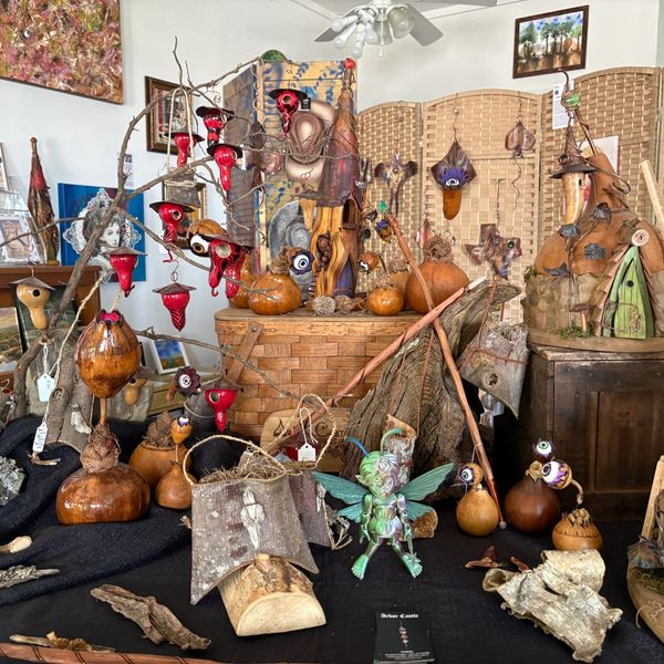 Handcrafted wooden and gourd art pieces with whimsical designs on display.