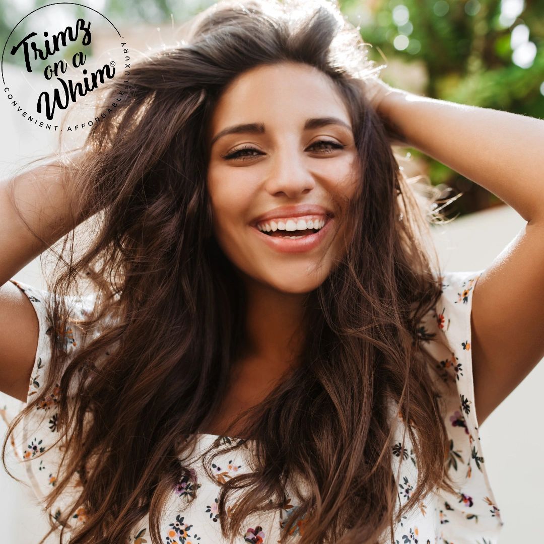 beautiful brown haired woman smiles openly while touching hair wiih both hands