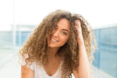 woman with mixed texture long curly hair  smiles at camera