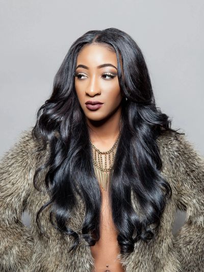 beautiful woman with long sew in weave stikes a pose in a fur coat