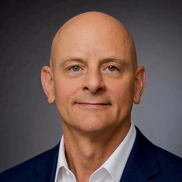 Portrait of a bald middle-aged man in a suit.