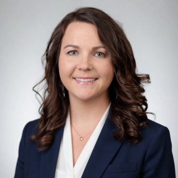 Professional woman with curly brown hair in business attire.