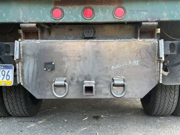 Rear view of a truck with a metal hitch and dual tires.