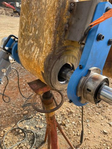 Close-up of heavy machinery bearing with blue mounting and rusted parts on a construction site.