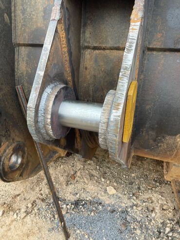 Close-up of a heavy-duty metal pin joint on machinery with visible welds.