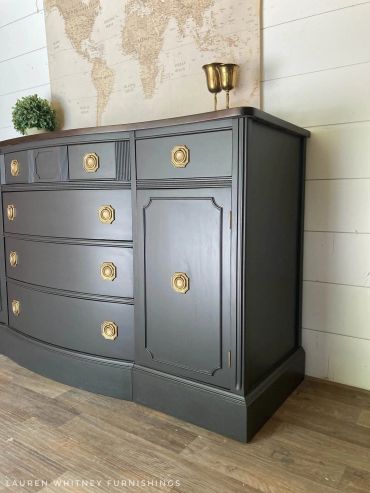Dark grey dresser with gold handles and decor.