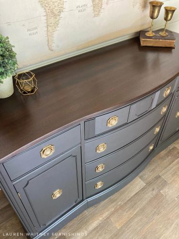 Elegant dark wooden sideboard with gold handles and decor.