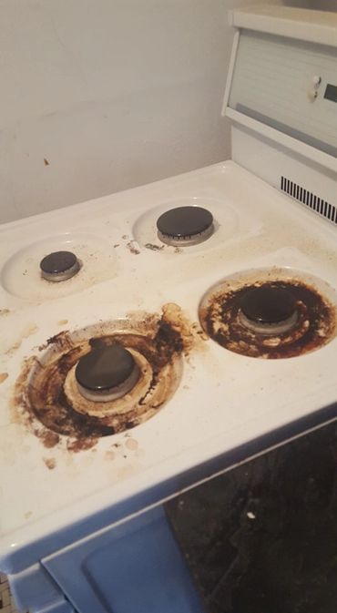 A dirty stove with burnt residue and grime around the burners.