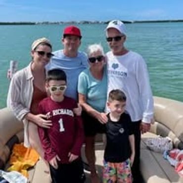Family enjoying a sunny day on a boat by the water.