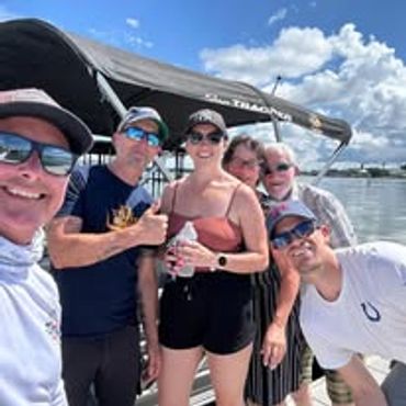 Group of five friends enjoying a sunny day on a boat.