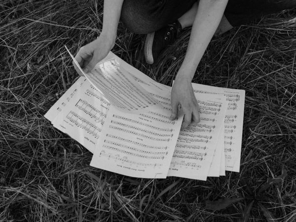 Person flipping through sheet music outdoors.