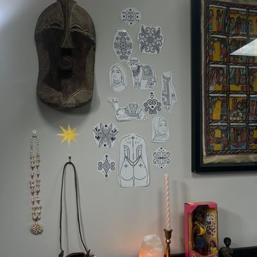 A wall decorated with tribal art, sketches, and cultural artifacts.