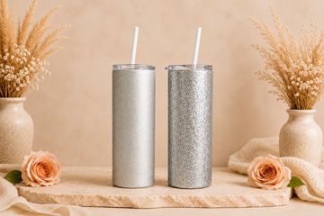 Two glittery tumblers with straws on a table.