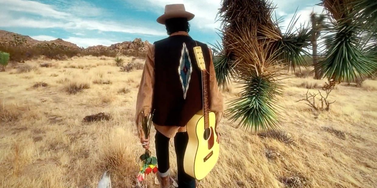 Walking the desert with guitar and flowers
