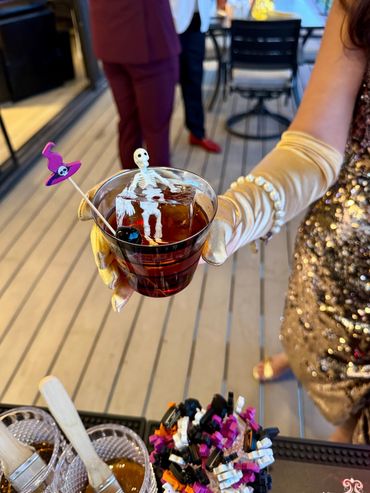 A spooky Halloween cocktail with a skeleton ice cube and witch hat stirrer.