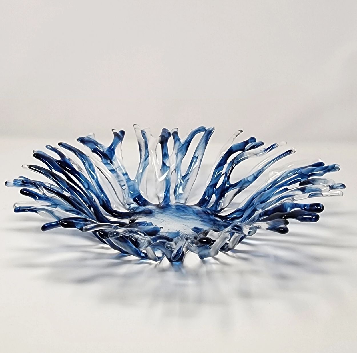 Artistic blue and clear glass bowl with a wavy design.
