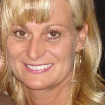 Close-up portrait of a smiling blonde woman with light makeup.