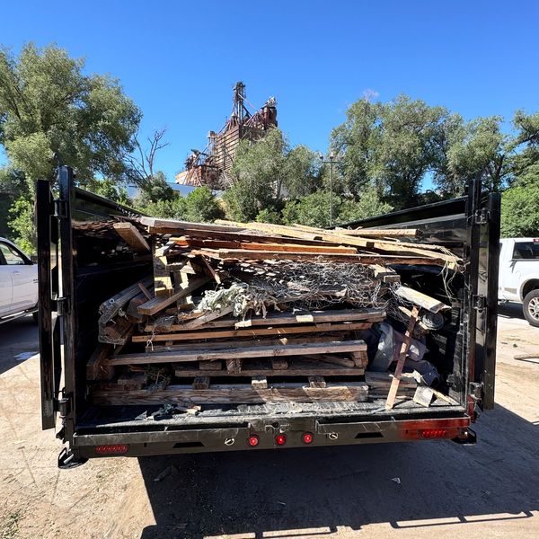 Trailer loaded with scrap wood and debris on a sunny day.