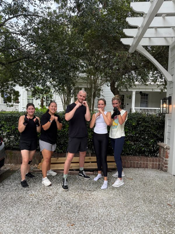 Group of five people posing with boxing stances outdoors.