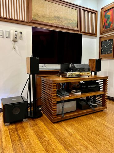 Modern entertainment setup with TV, speakers, and wooden furniture.