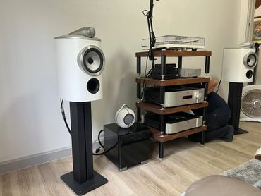 High-end audio setup with white speakers, amplifiers, and a turntable in a modern room.