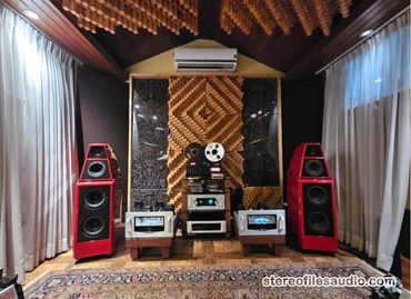 High-end audio setup with large red speakers and vintage reel-to-reel tape recorder.