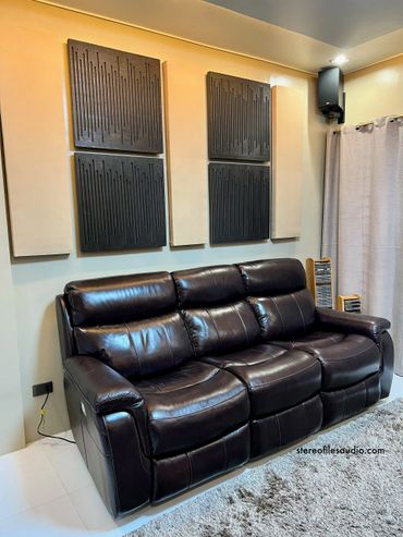 Black leather recliner sofa with acoustic panels on the wall.