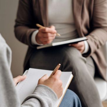 Two people writing in journals