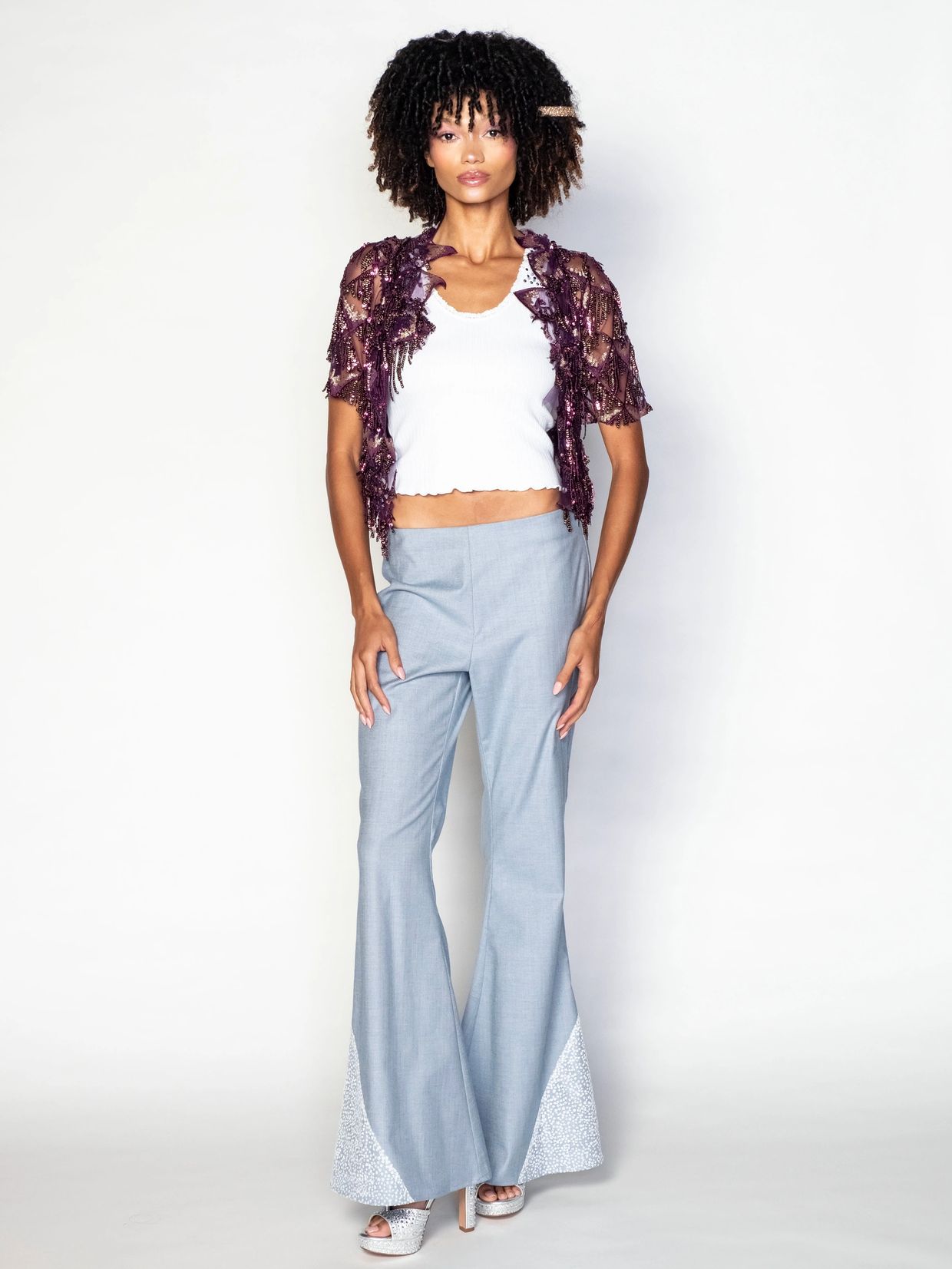 Fashion model in trendy outfit posing against white background.