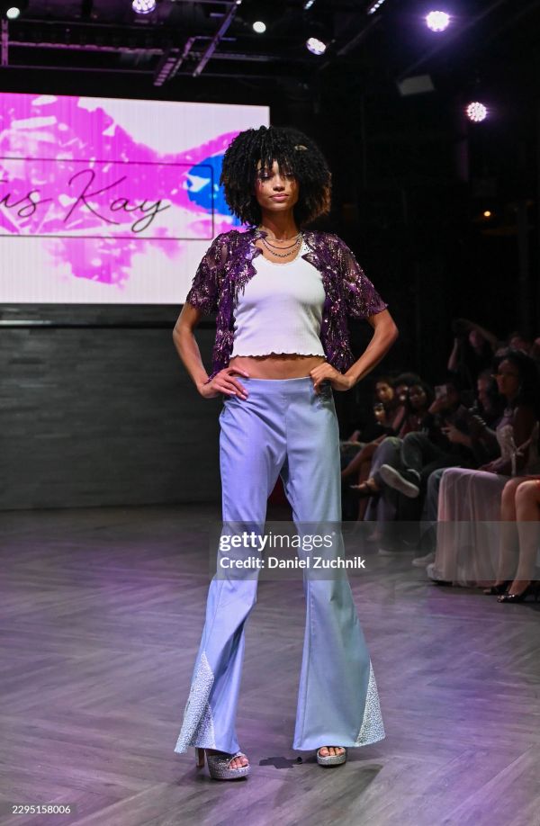 Model walking on runway in stylish outfit.