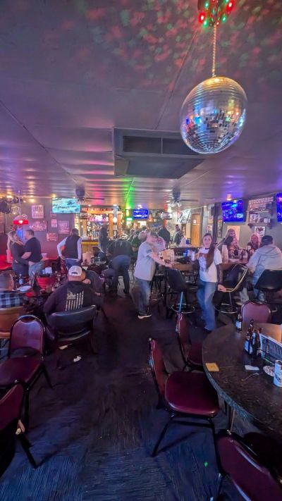 Crowded bar scene with disco ball and people socializing.