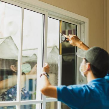 A person cleaning a sliding glass door with a squeegee.