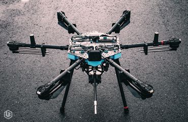 A wet, six-armed drone on asphalt with Lucid branding.