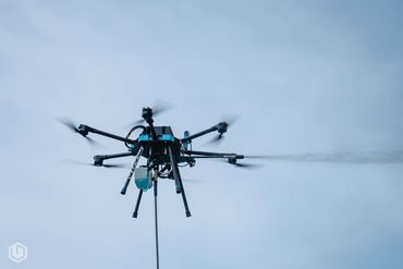 A drone spraying liquid against a clear sky background.