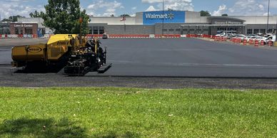 A Walmart parking lot is being resurfaced under a sunny sky.