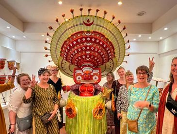 Group of women posing with a person in a vibrant traditional costume.