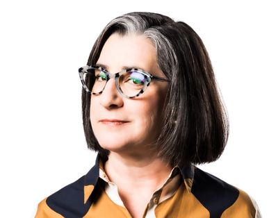 Confident woman with glasses and salt-and-pepper hair.