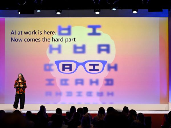 A speaker presents on AI with an eye chart-themed backdrop at a conference.