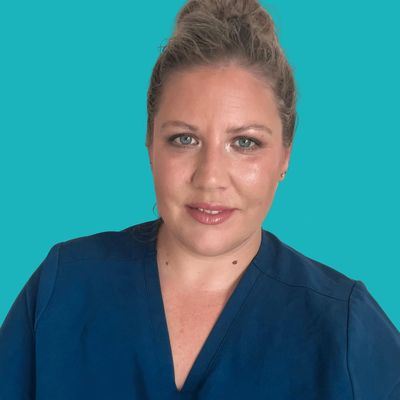 Portrait of a woman in blue scrubs against a turquoise background.