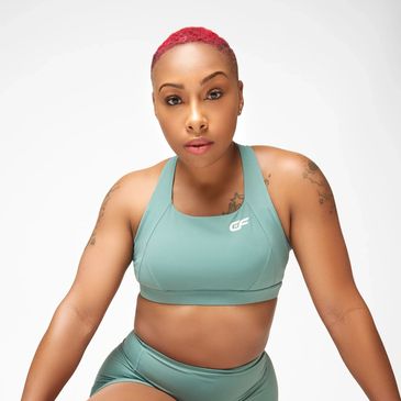 Woman with red hair in teal workout outfit sitting on the floor.