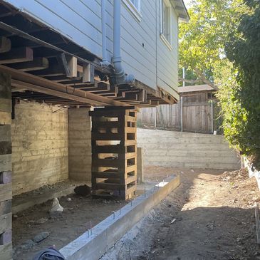 House elevated on wooden supports during construction work.