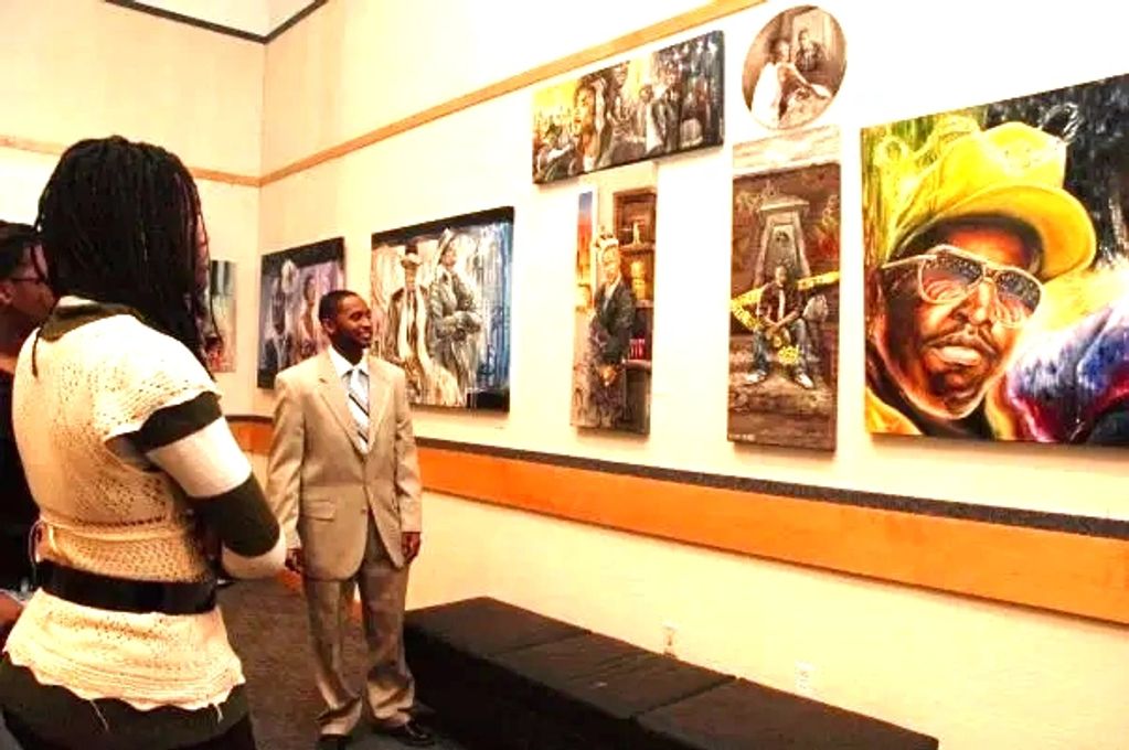 artist in tan suit explaining painting to an audience with portraits in background