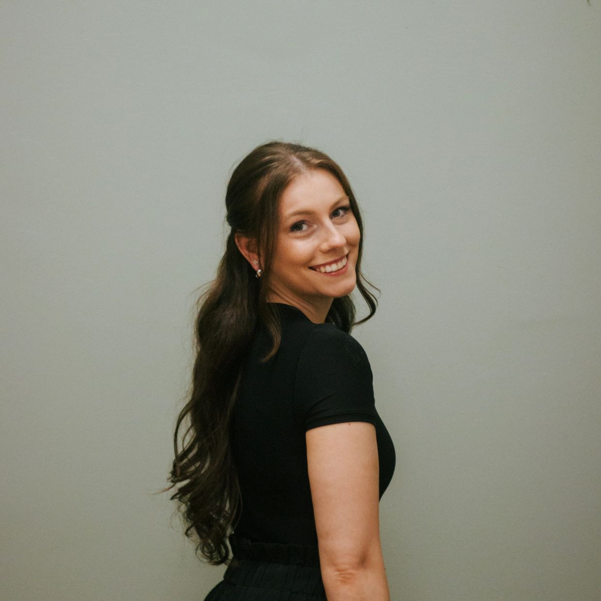 Smiling woman with long hair in black outfit.