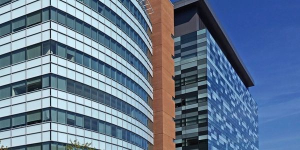 Modern hospital building with glass facade under clear blue sky.