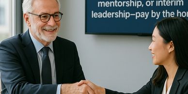 A seasoned grey-haired consultant warmly shaking hands with a younger executive.