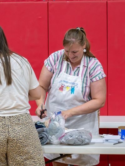 Woman in apron assisting two customers at a table with items.