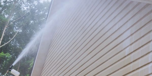 Pressure washing a house exterior siding.